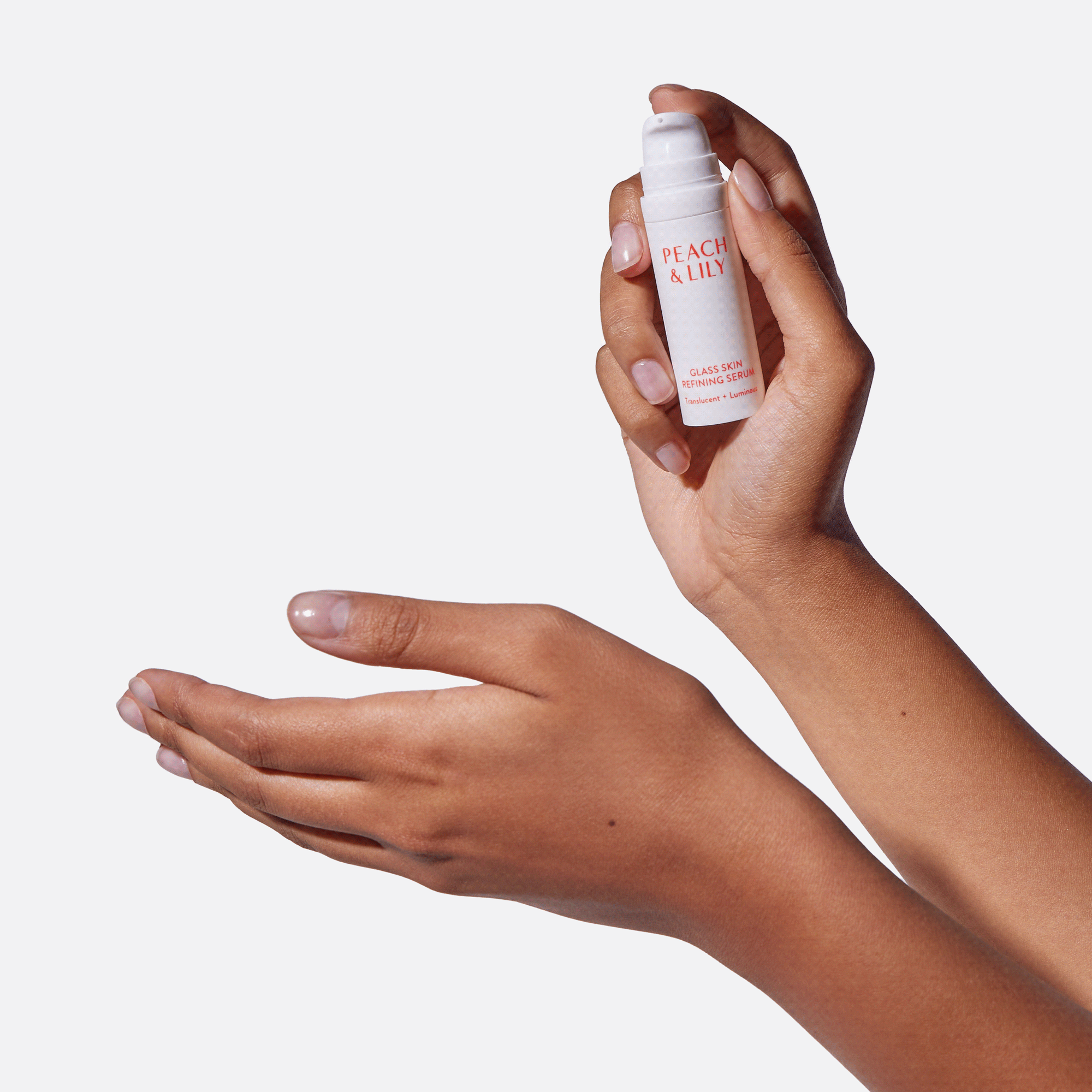 Someone uses a pump of the Peach & Lily Travel Size Glass Skin Refining Serum on their hand, showing how the pump bottle easily fits in their hand and the product is easy to spread across the skin