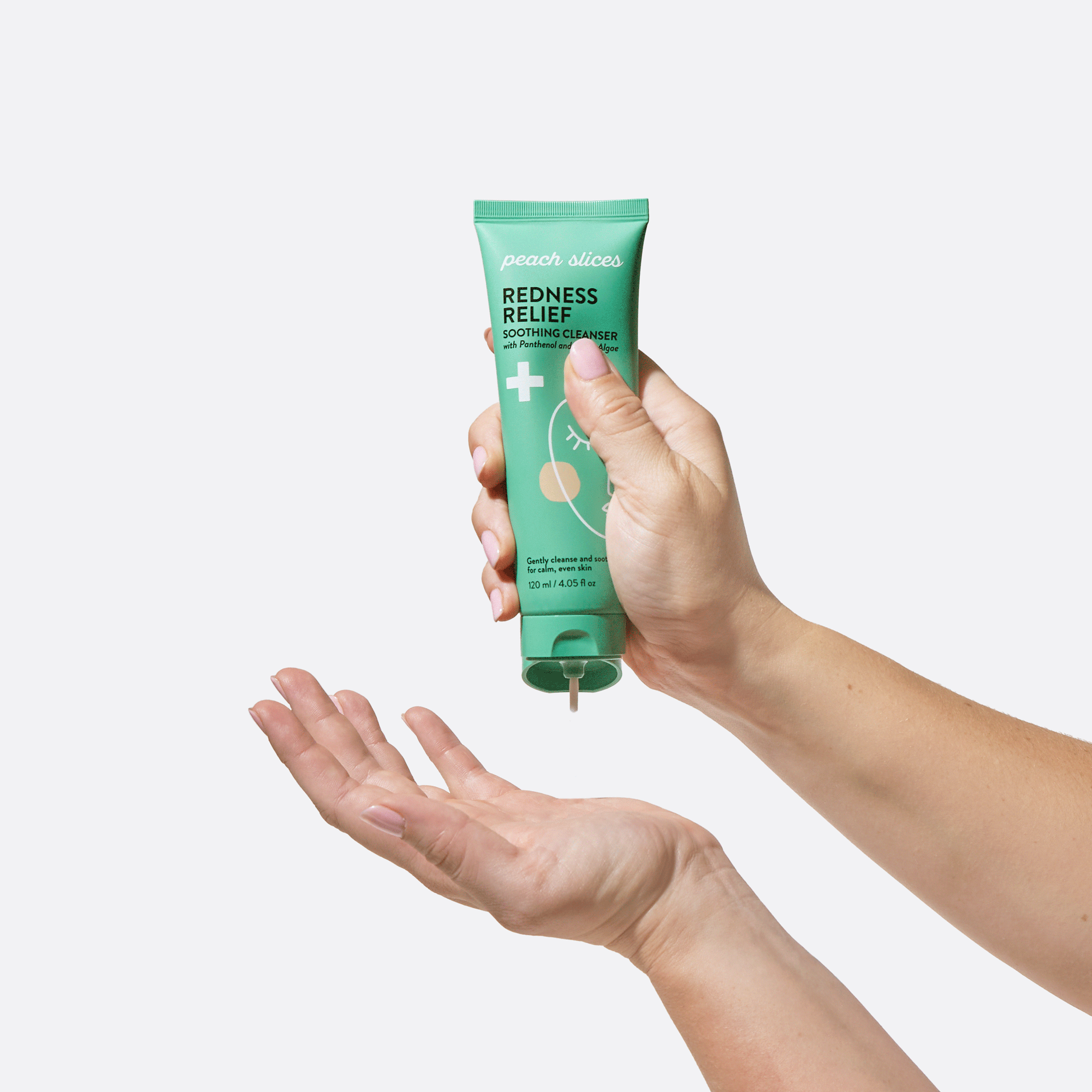 Someone squeezes out Redness Relief Soothing Cleanser into their hand, showing off the easy-squeeze bottle and smooth texture of the product