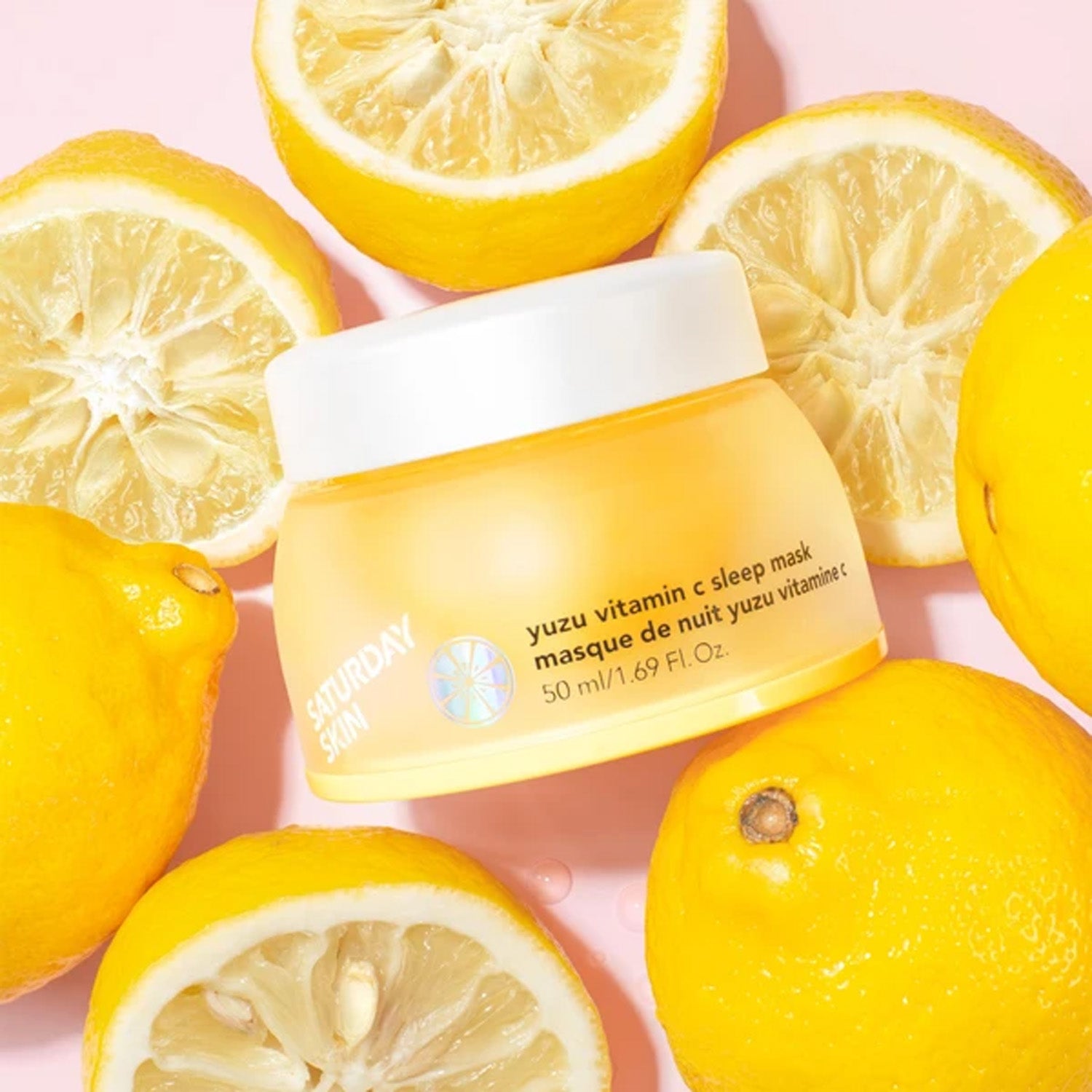 A jar of Saturday Skin Yuzu Vitamin C Sleep Mask surrounded by lemons