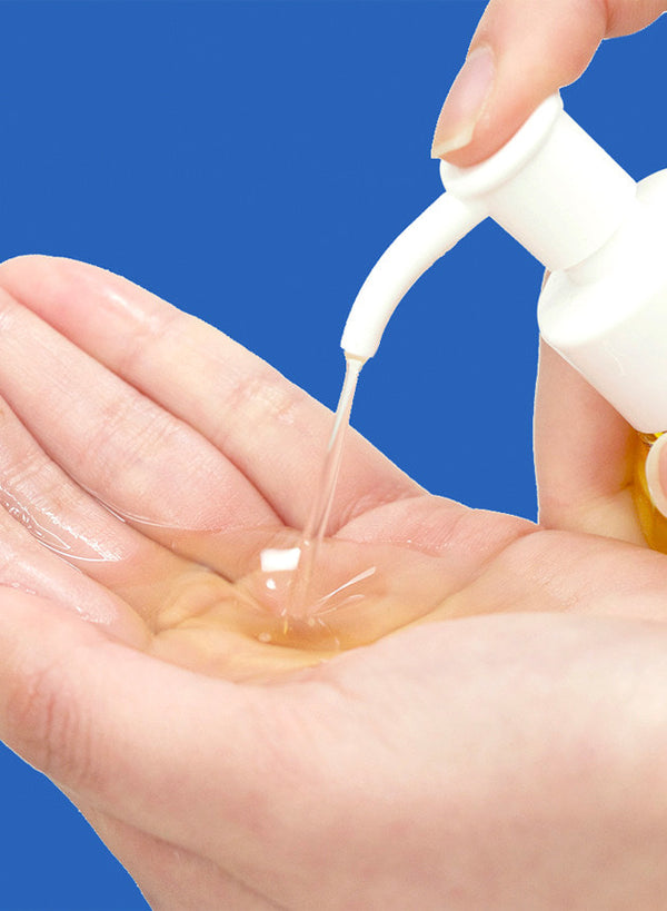 Someone pumps the Ma:nyo Pure Cleansing Oil into their hand, showing off the oily texture and easy use of the pump