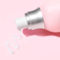 A bottle of Saturday Skin Wide Awake Brightening Eye Cream squeezes out a line of cream, showing how easy it is to control the amount that comes out of the bottle