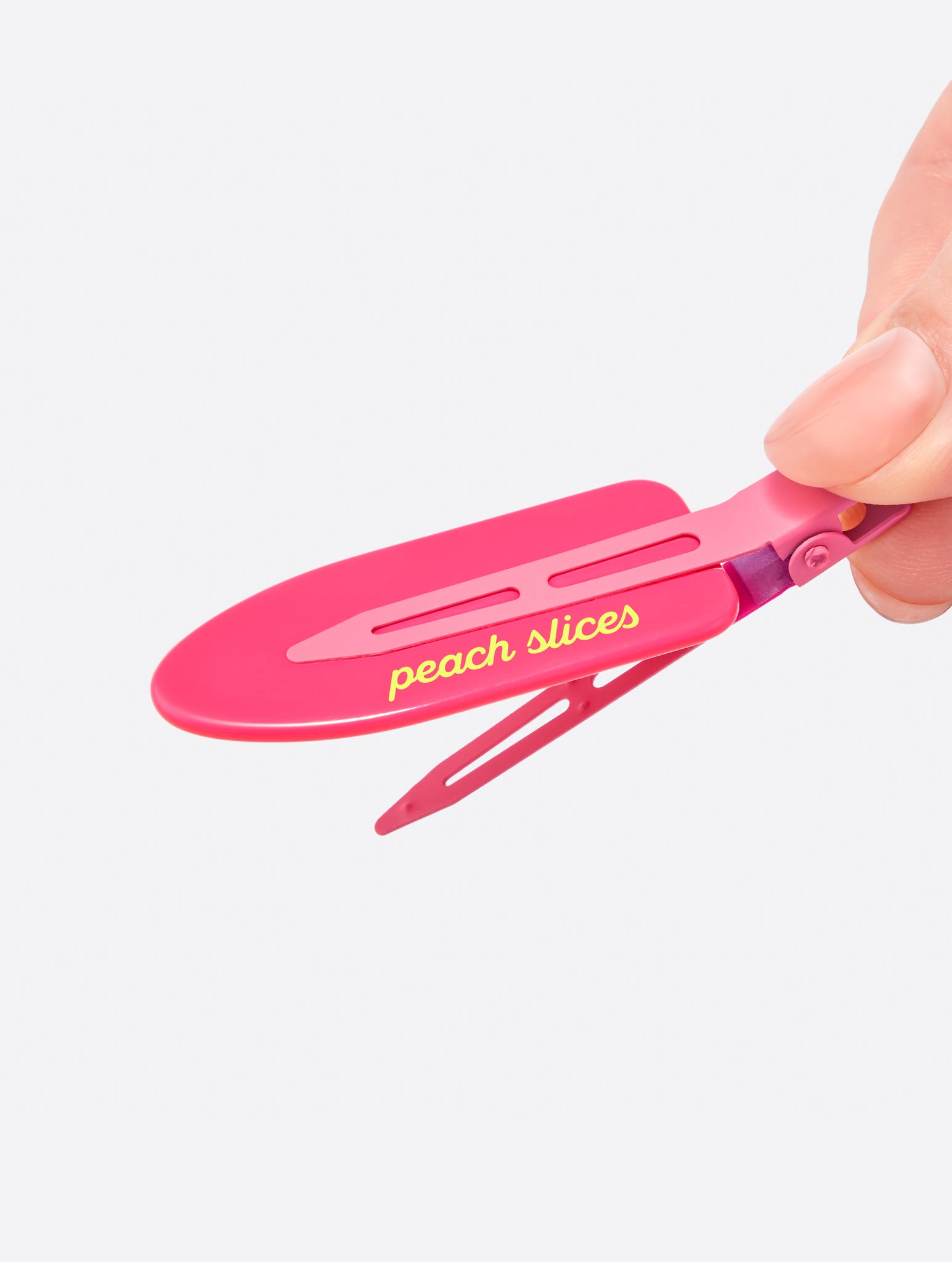 A close-up of a hand holding a pink Creaseless Hair Clip
