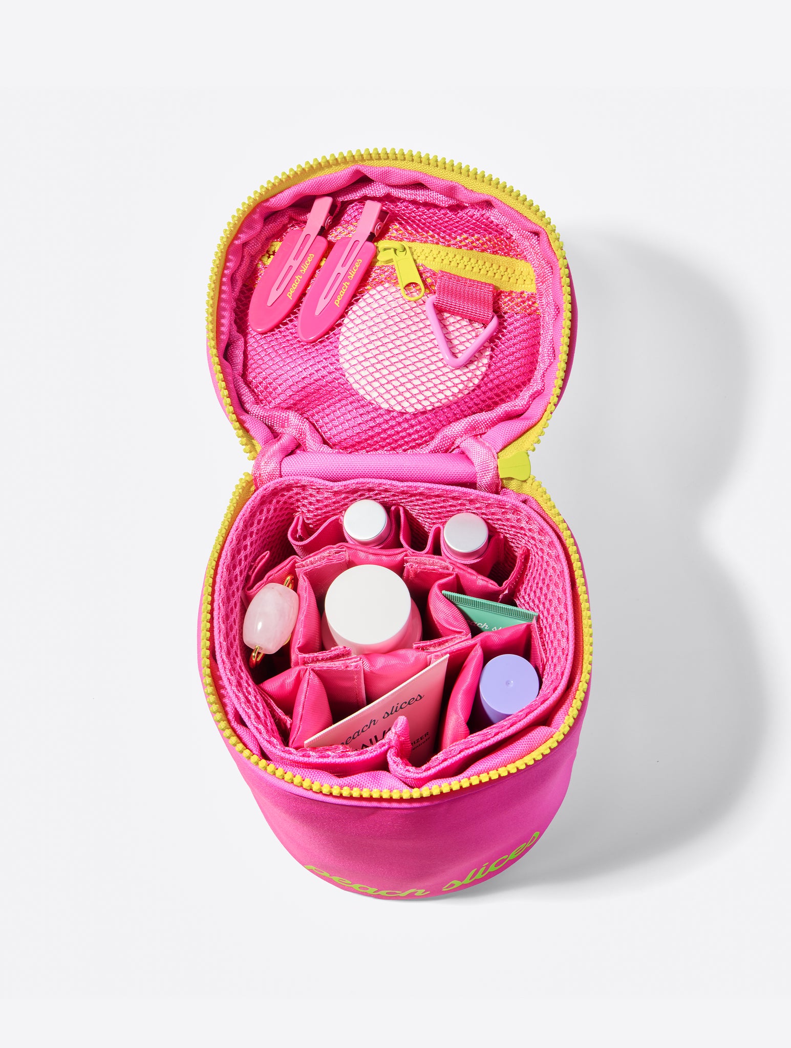 Open pink Peach Slices standing makeup bag showing various compartments for makeup and skincare products